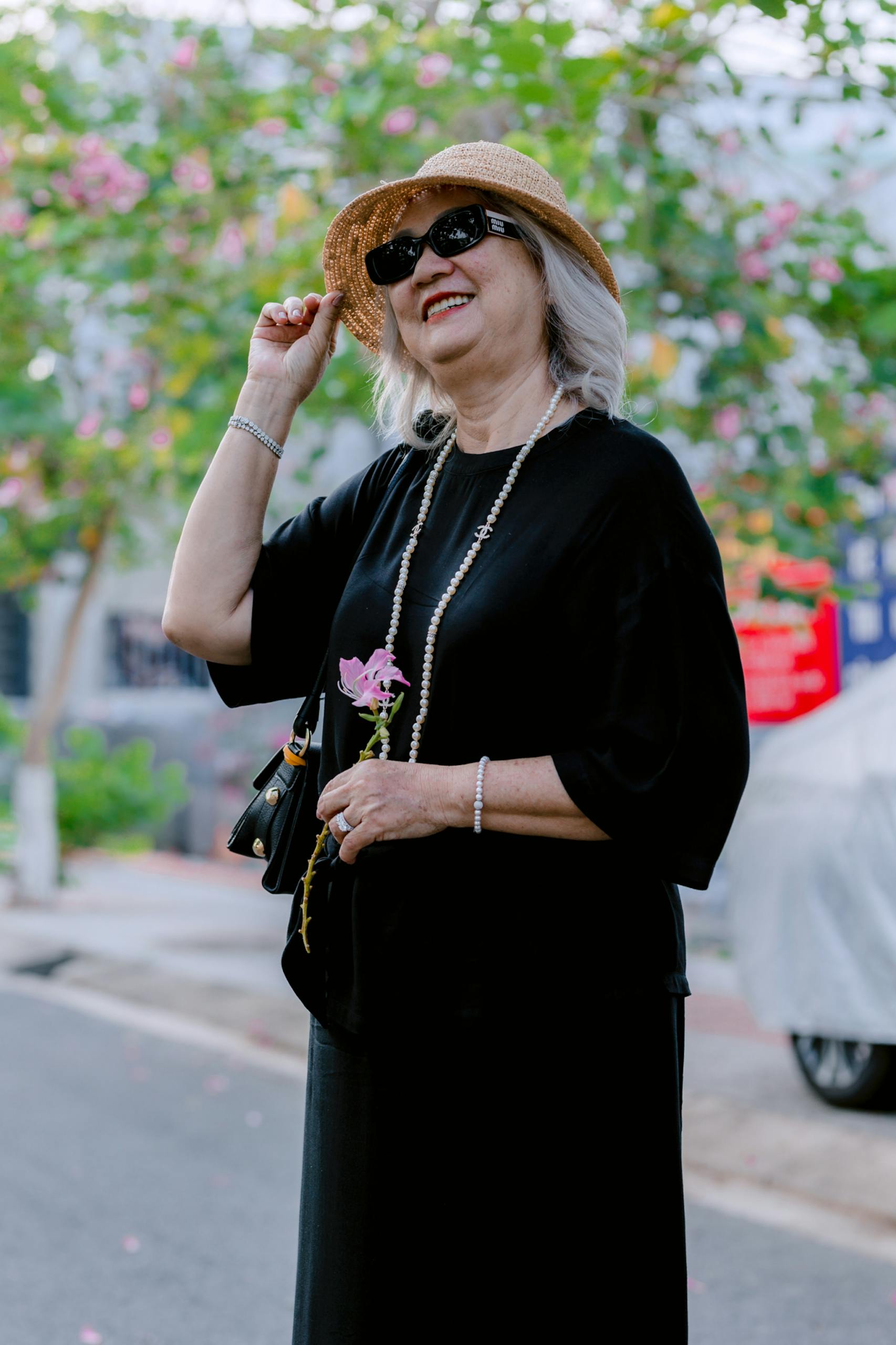 Elegant senior woman in sunglasses and sunhat enjoying a sunny day outdoors.