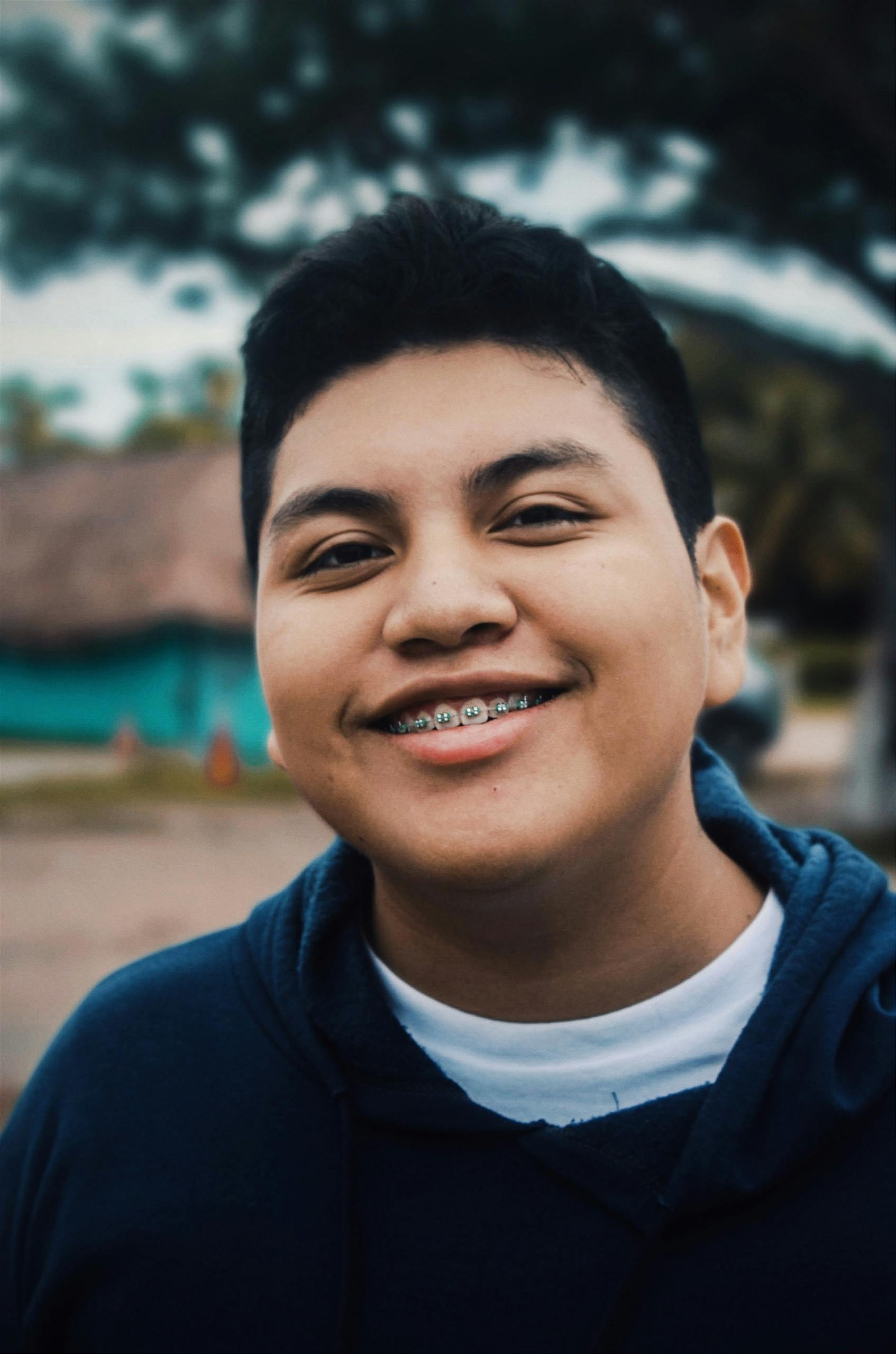 Portrait of a smiling teenager with braces wearing a hoodie in Bacalar, Mexico.